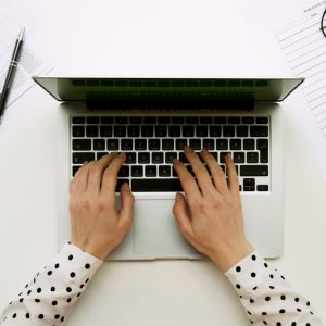Person skriver på laptop ovanifrån